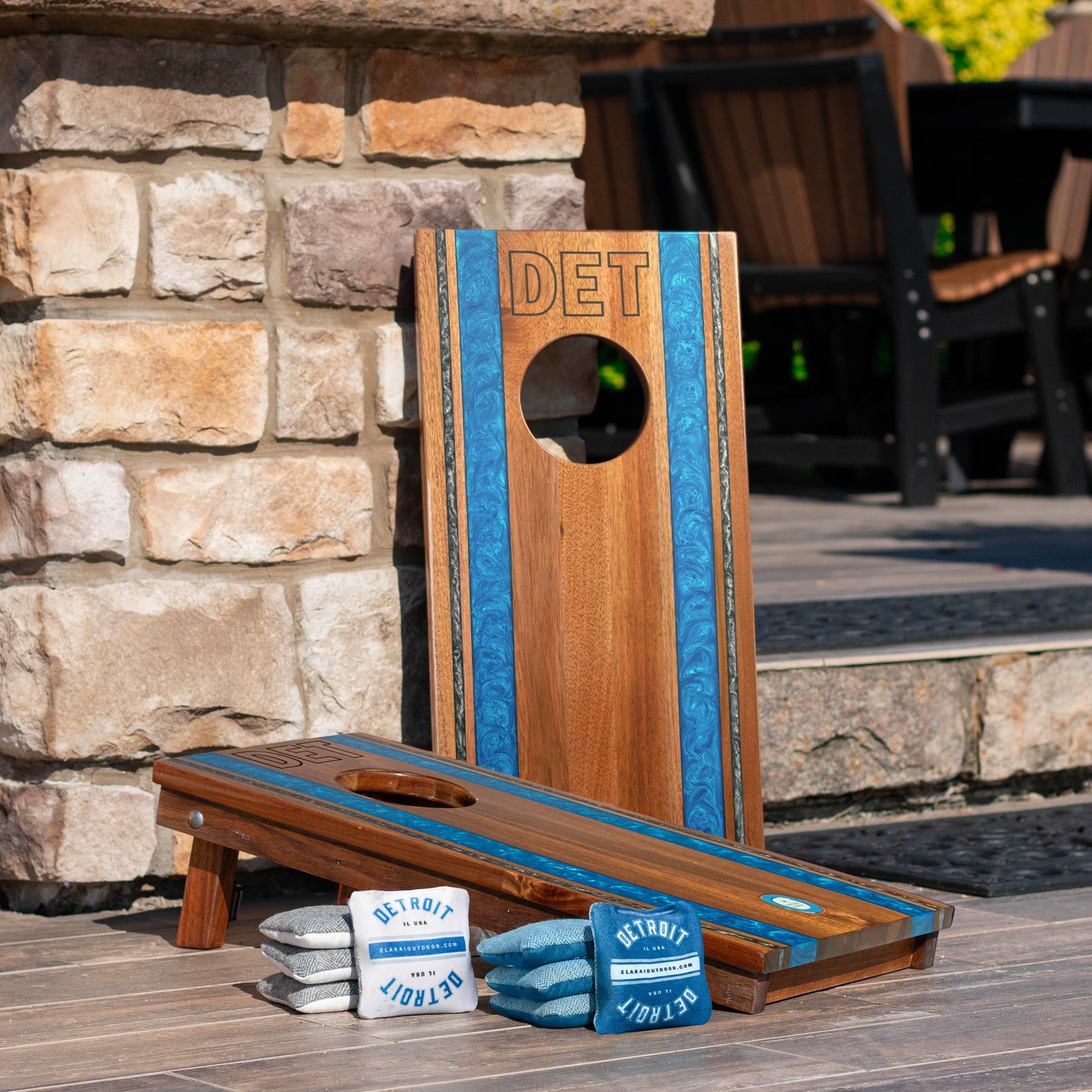 Wooden cornhole boards with 'DET' branding on a patio with stone wall background
#color_detroit