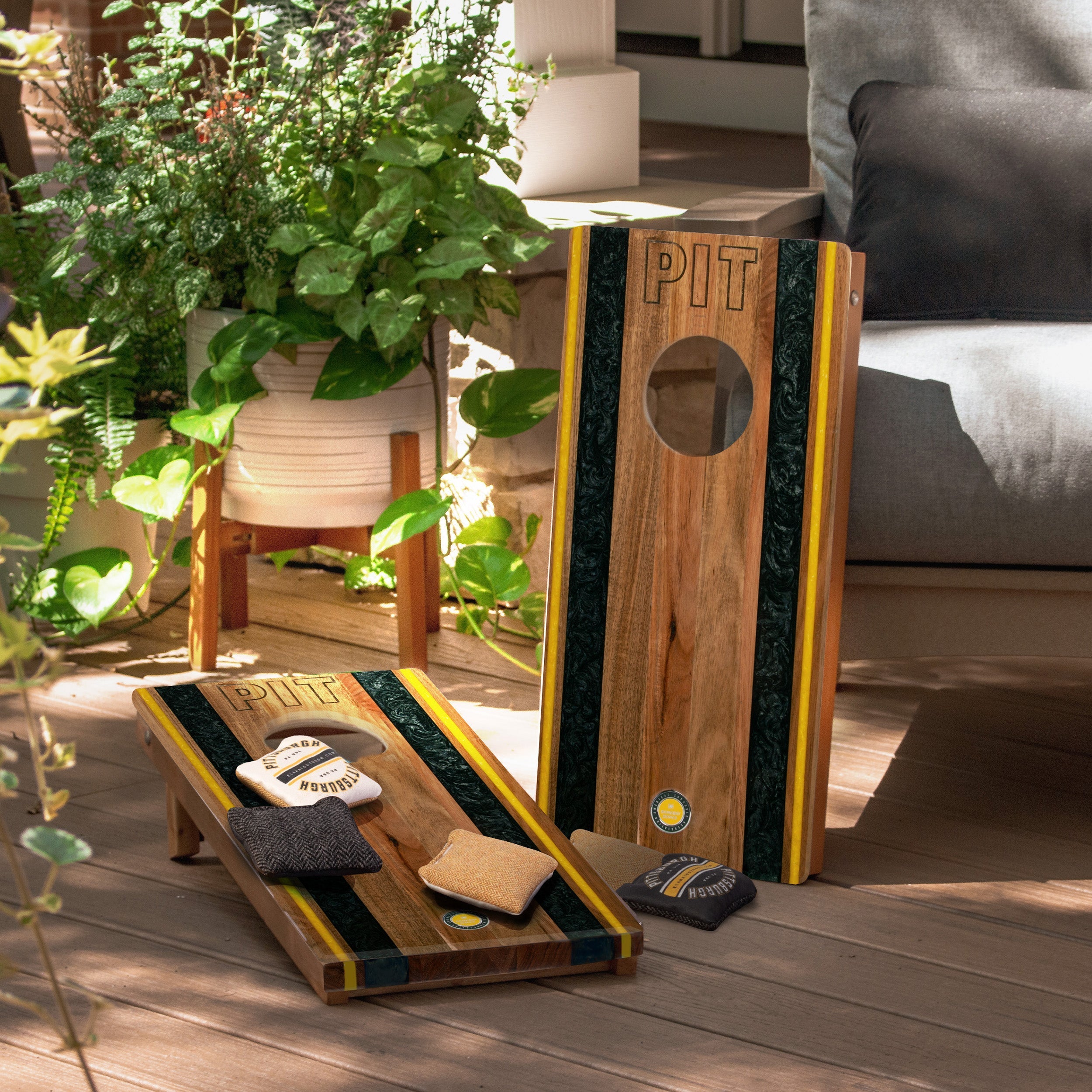 Wooden cornhole boards with bags on a wooden deck, surrounded by plants and furniture.
#color_pittsburgh