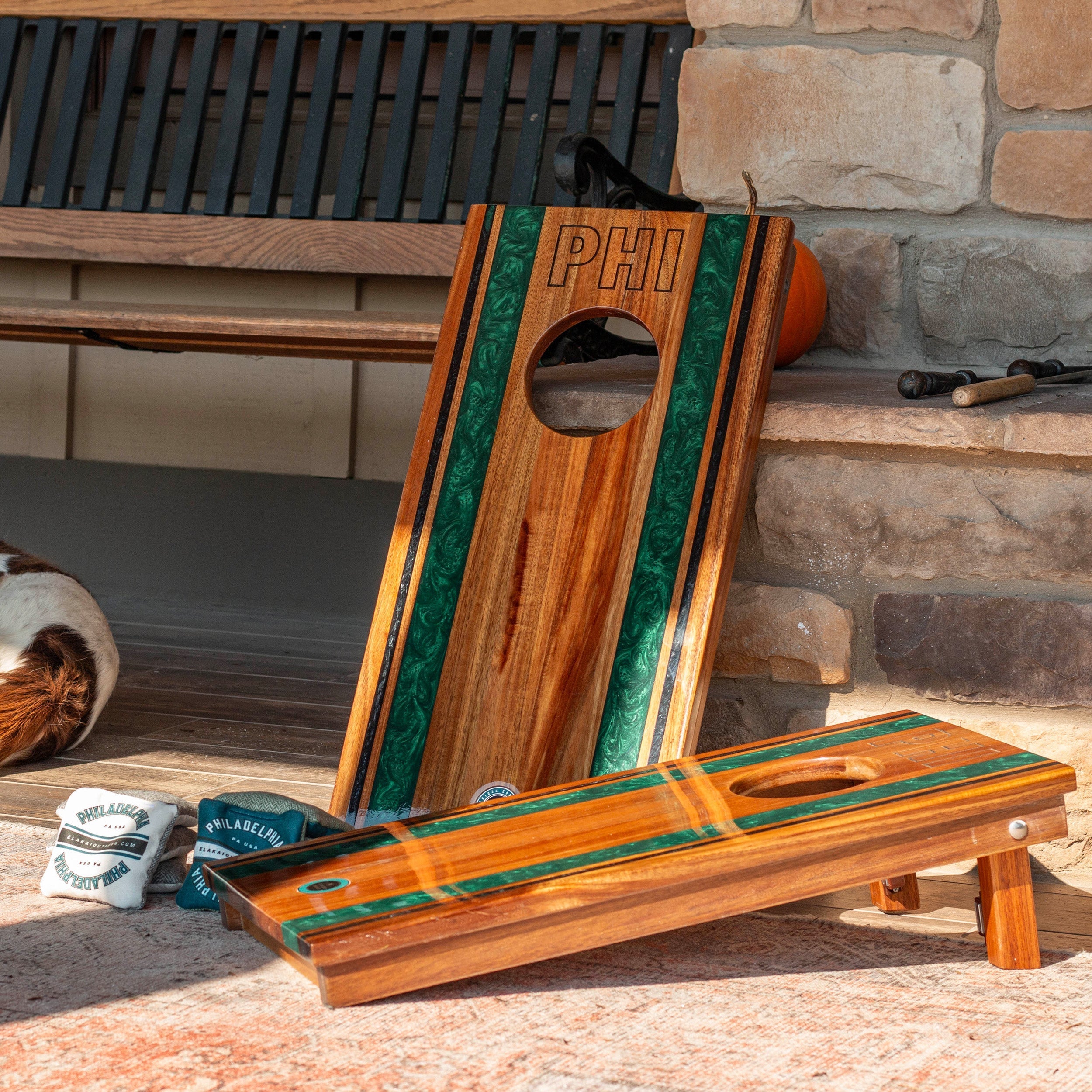 Wooden cornhole boards with green stripe and 'PHI' branding on a stone patio.
#color_philadelphia