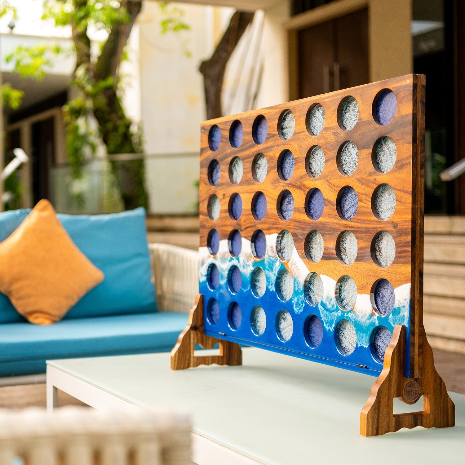 Beach Resin giant four in a row yard game set up on an outdoor patio table beside lounge seating