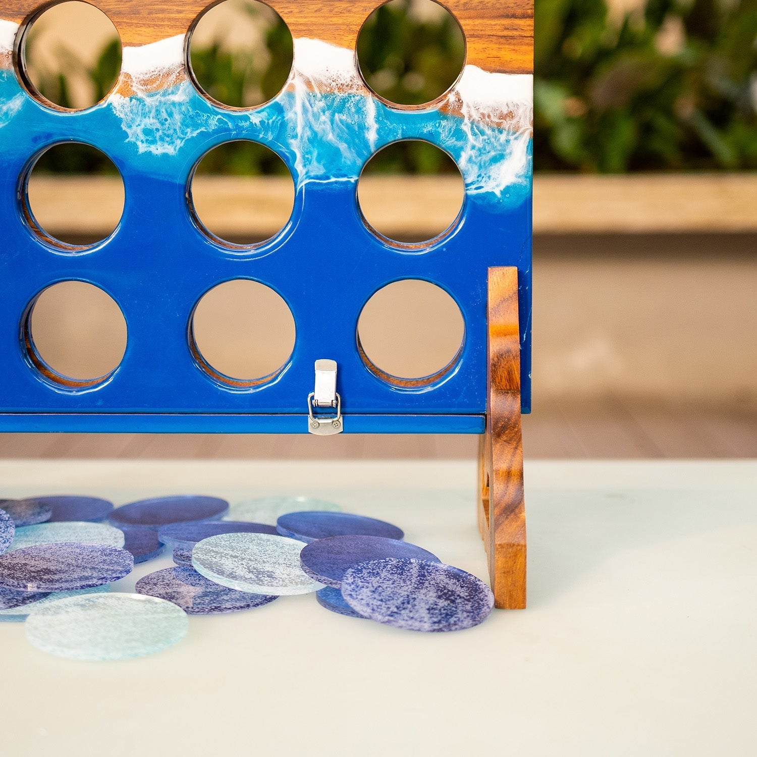 Lower board of the Beach Resin giant 4 in a row game showing drop-in holes, glossy blue resin, and folding latch